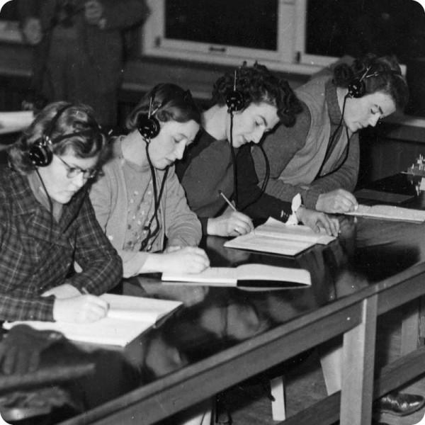 four students with headphones and notebooks seated in a row
