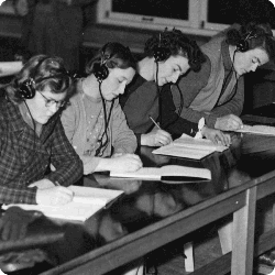 four students with headphones and notebooks seated in a row